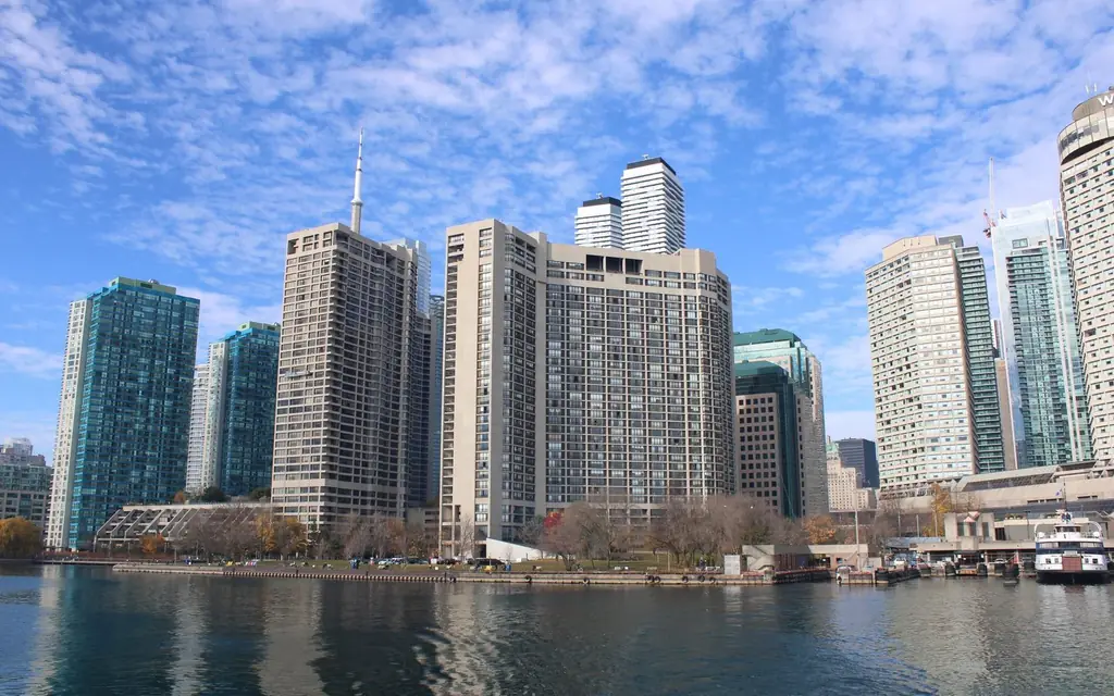 Toronto's urban skyline with modern skyscrapers reflecting on a calm body of water.
