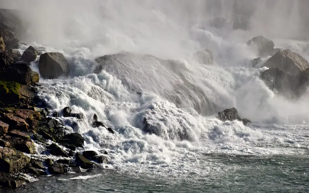 Dramatic view of the roaring waters cascading over rocks at Niagara Falls, Ontario.