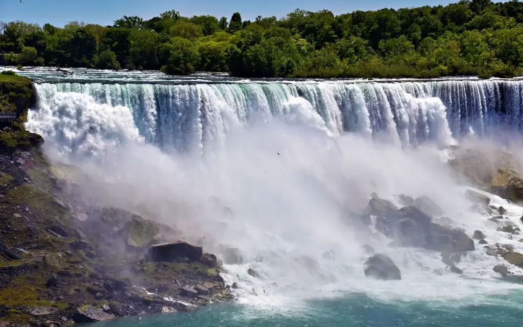 Breathtaking view of Niagara Falls captured in vibrant summer sunlight with lush green surroundings.